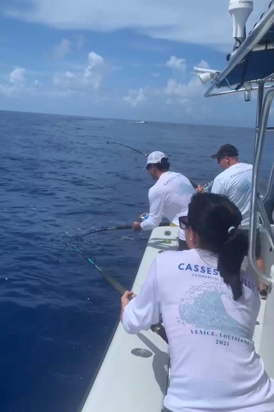 Three people fishing off the side of a boat in the Gulf of Mexico.