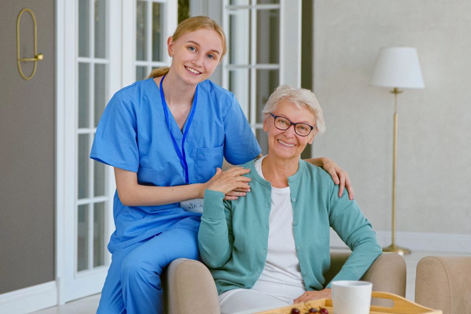 A elderly woman and her assisted living caretaker smiling