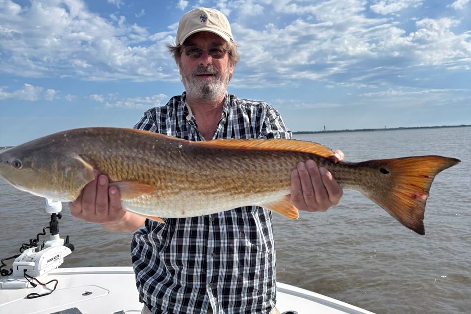 Angler holding a trophy redfish caught during an inshore fishing trip in Charleston, SC