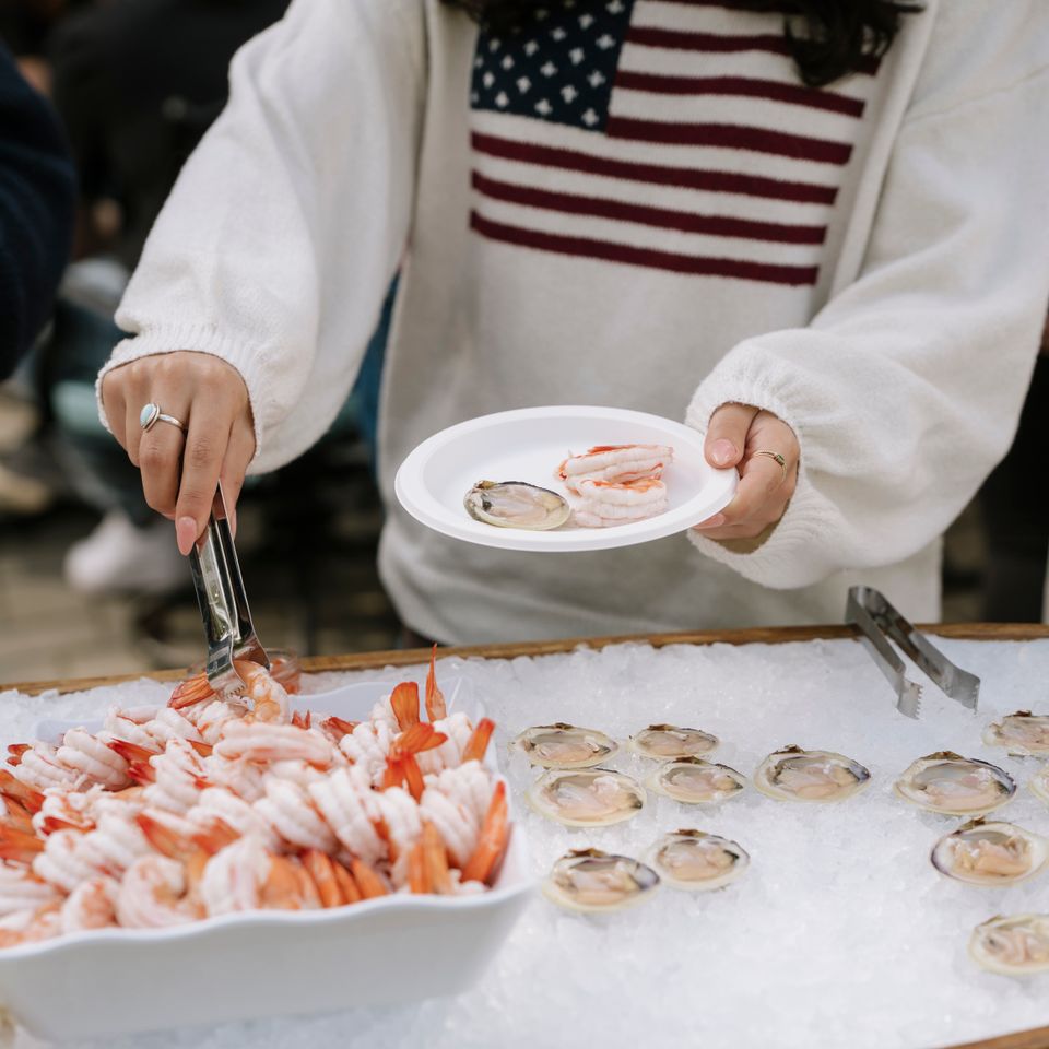 A woman picking pieces of shrimp from a raw bar, done by Shore2Shore Shucking of Long Island