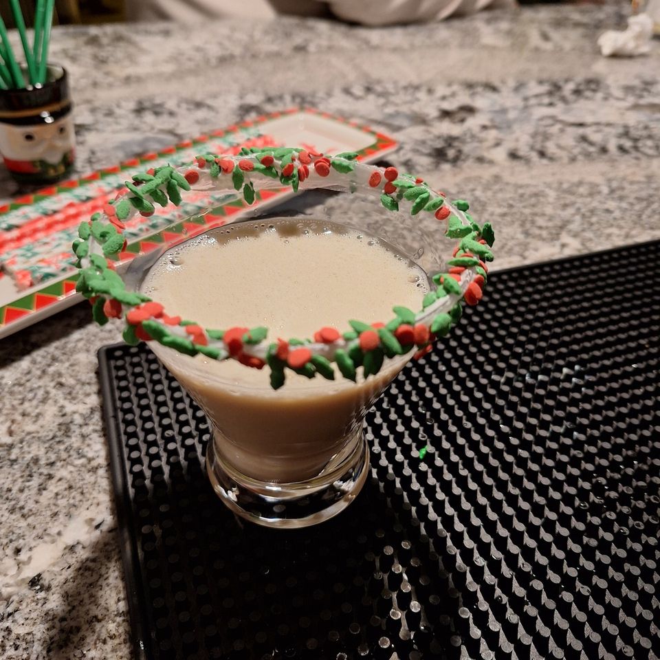 Sugar cookie martini with red and green sugar rim in a glass on a bar mat