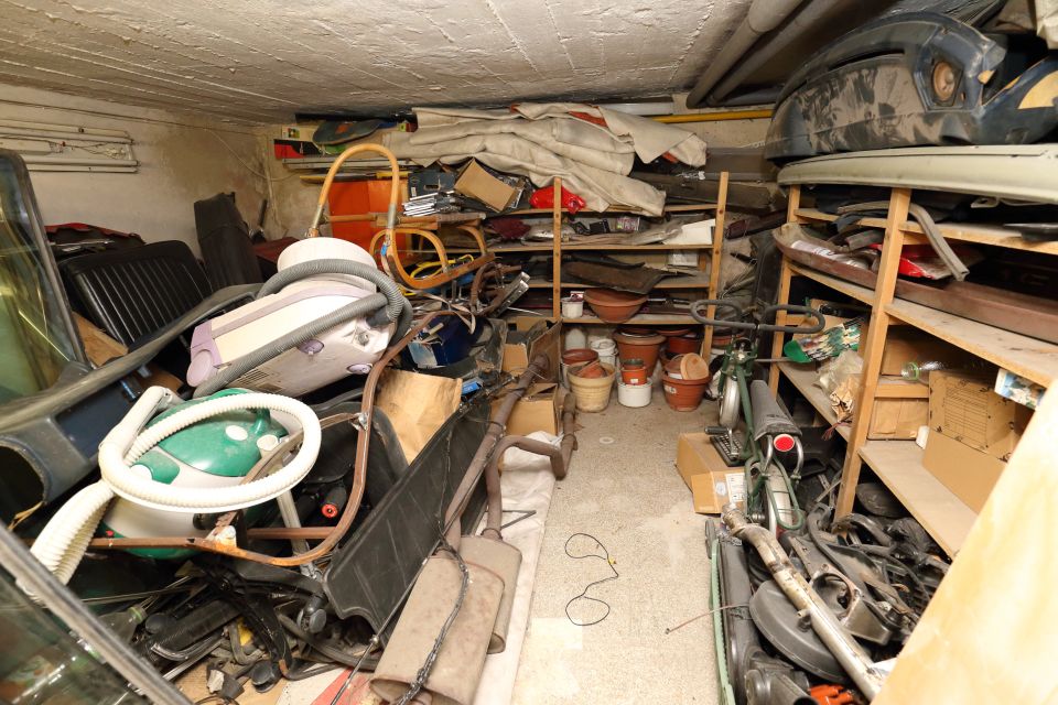 Low cellar full of trash, old vacuum cleaners and vehicle parts
