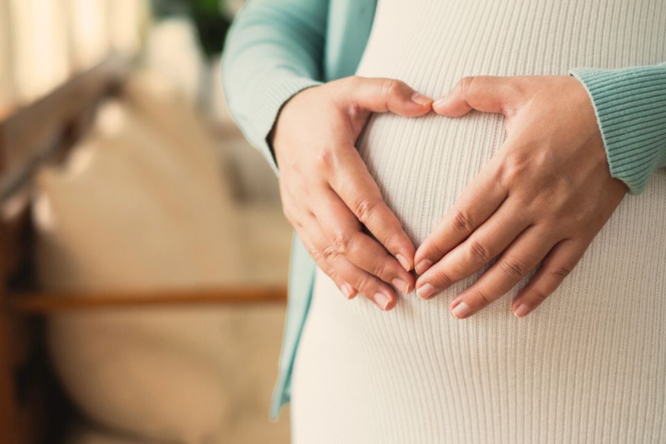 Pregnant woman holding her belly during prenatal pelvic therapy consultation