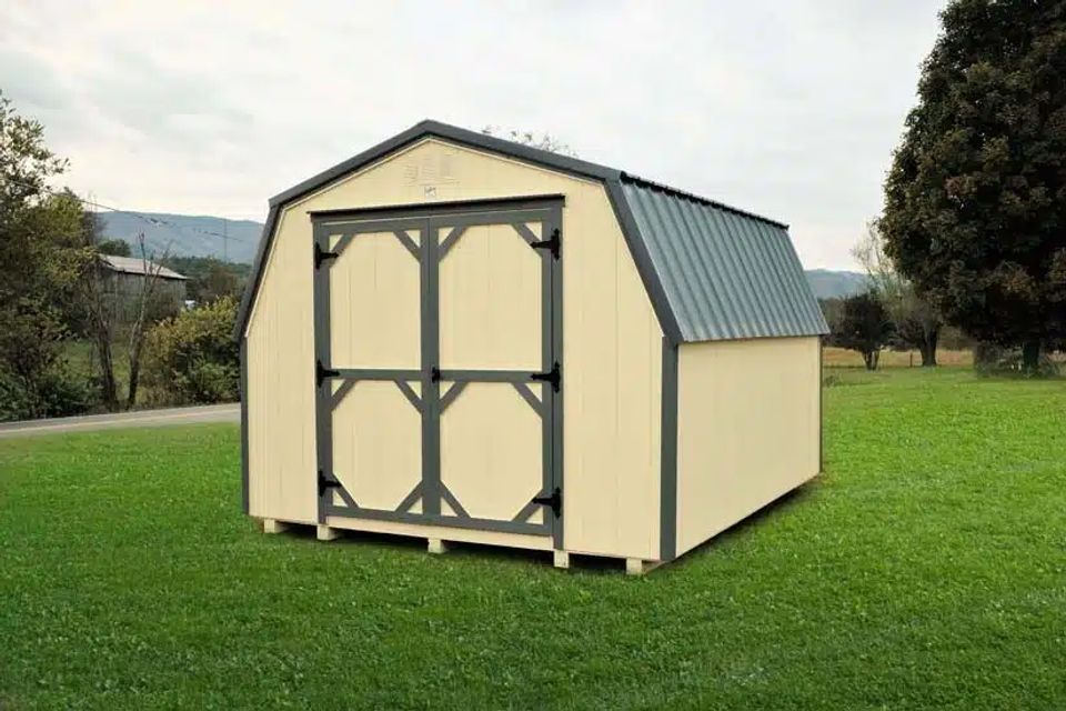 Cream mini barn shed with gray trim and double doors set on a grassy Elizabethton TN lot