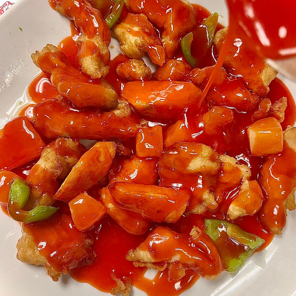 Freshly cooked entrée topped with vibrant red sauce and mixed vegetables on a white plate.