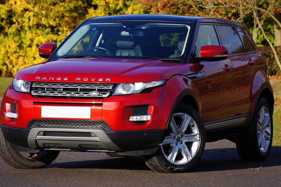 Red Range Rover on a street near wooded area