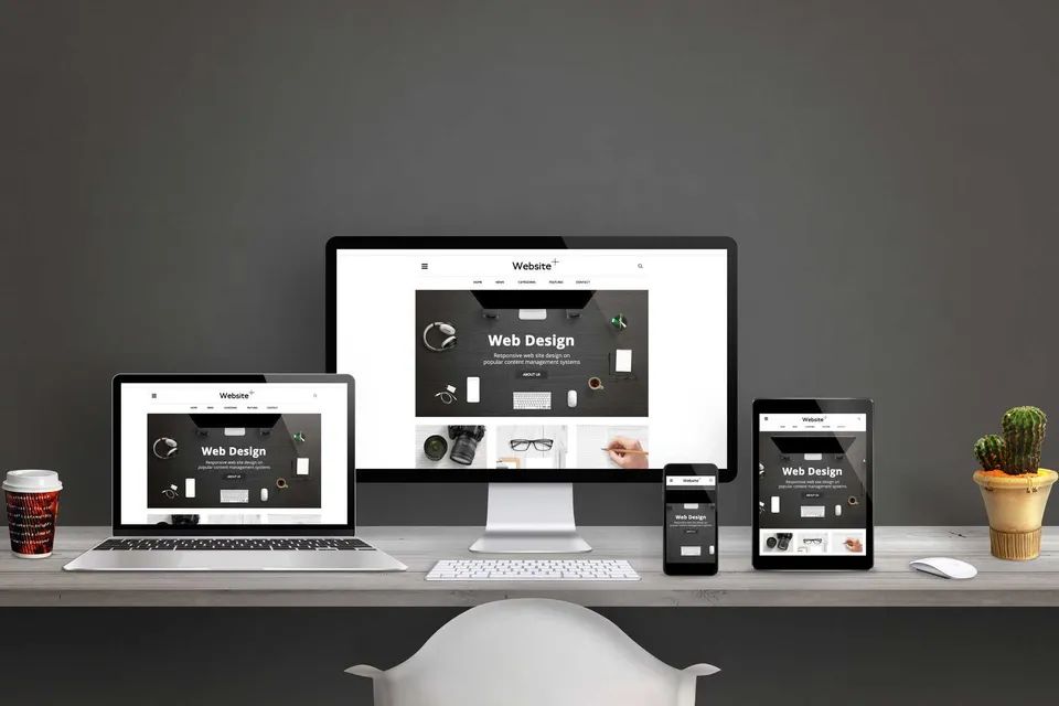 Website being designed and displayed on a laptop, desktop, tablet and mobile phone screen. Black room