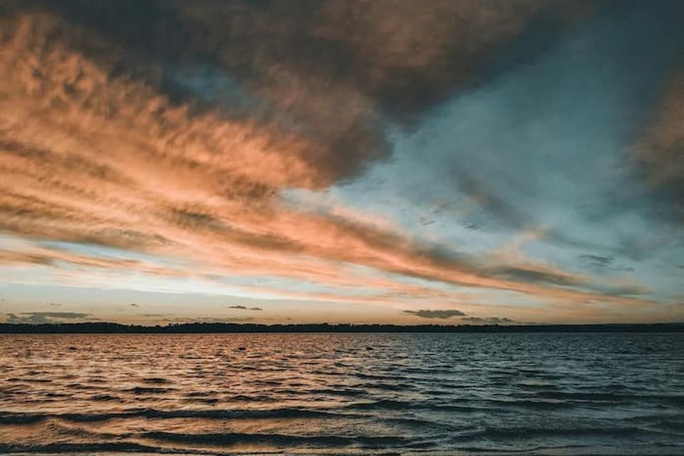 Sunrise over a body of water with oranges and blues displayed 
