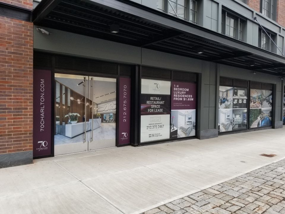Deep red and white printed vinyl panels on storefront windows and columns beneath a building canopy