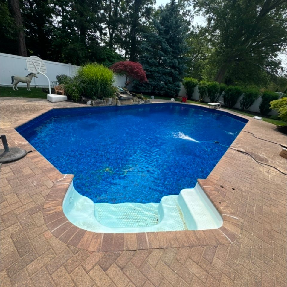 Freshly filled inground pool with new blue liner and paver patio at a Long Island NY home
