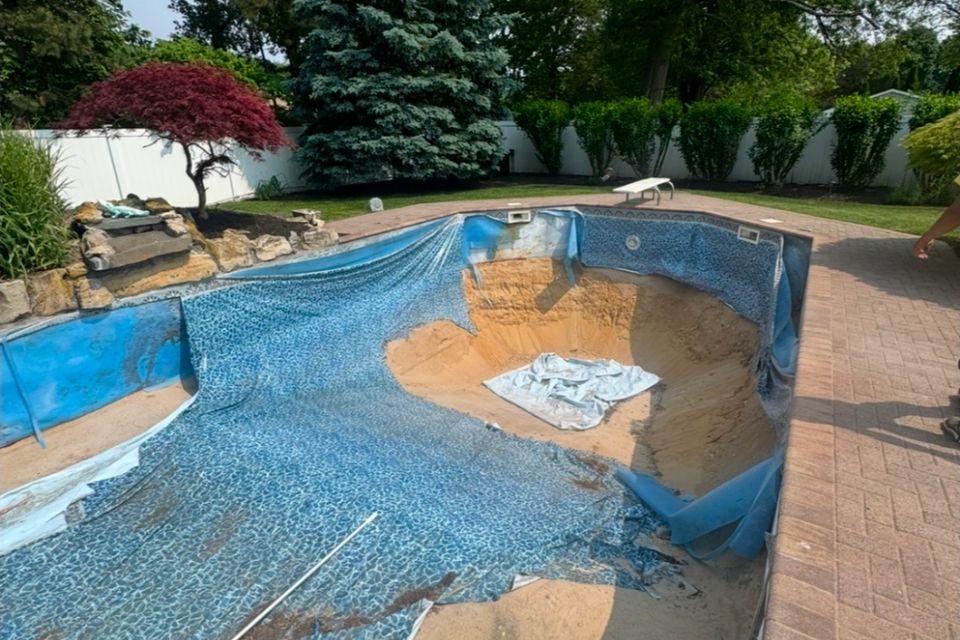 Old faded pool liner pulled back for liner replacement at a Long Island NY backyard pool