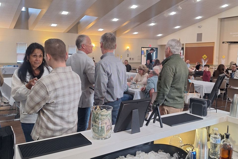 Guests socializing near a bar setup with drinks and garnishes at an indoor event