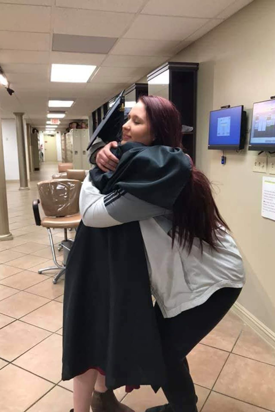 Beauty school students celebrating graduation with hug