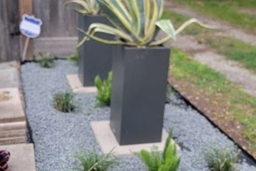Agave planters and Mexican‑beach‑pebble bed create a clean low‑maintenance landscape in Kingwood, TX