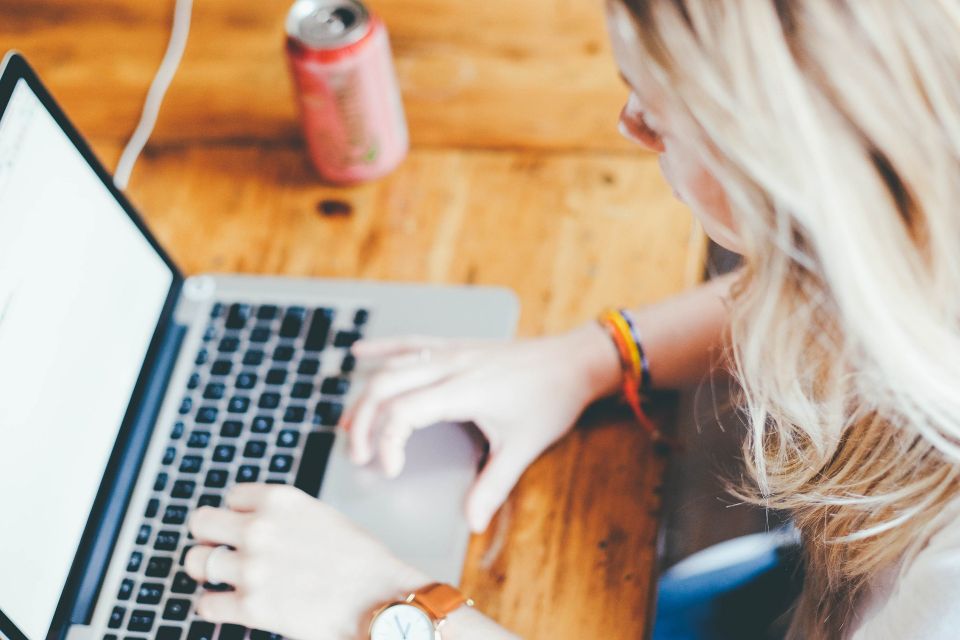 Blonde hair woman using keyboard navigation on her laptop 