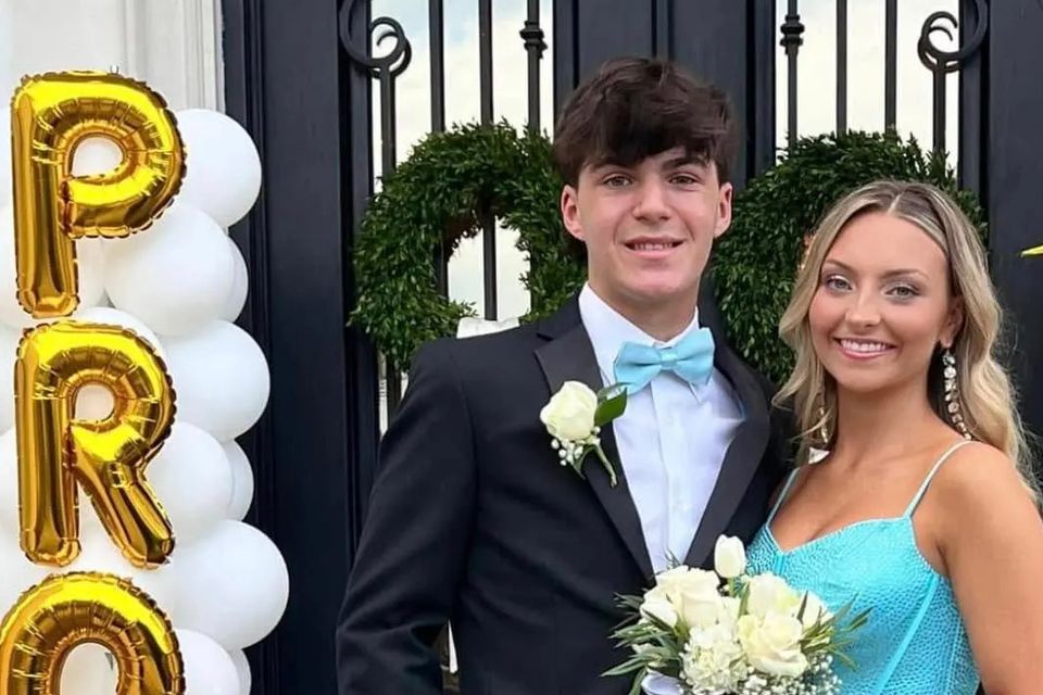 Teen couple dressed for prom, with the young man wearing a black suit and light blue bow tie.