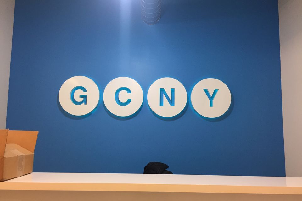 White dimensional letters on round white backers mounted across a blue interior reception wall above a counter