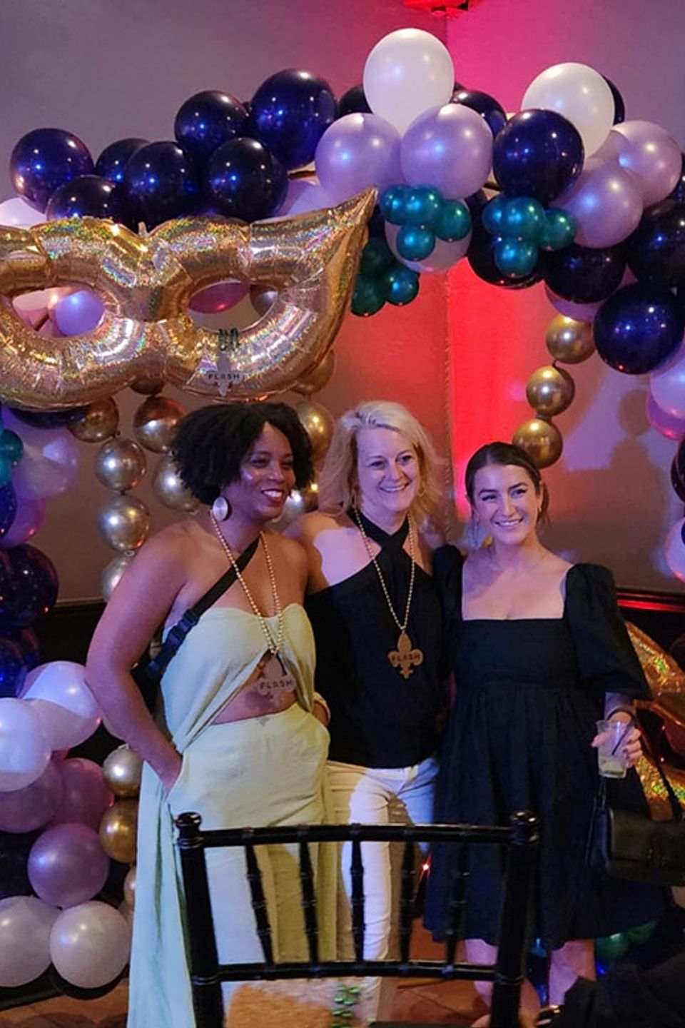 Guests posing in front of a Mardi Gras–themed balloon arch at a Carpe Diem Events celebration in New Orleans
