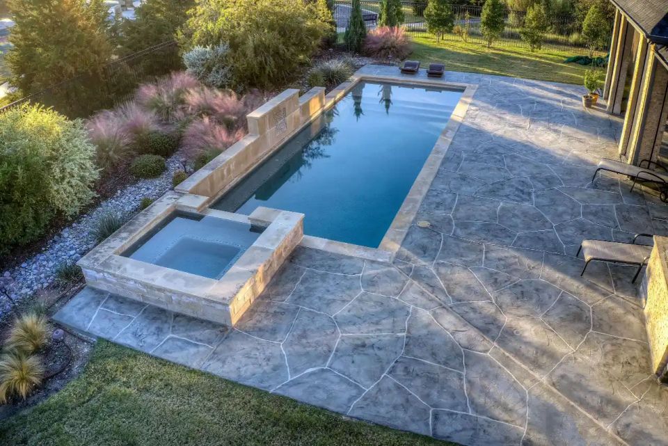  Luxury gray stamped concrete pool deck with custom spa and modern backyard landscaping