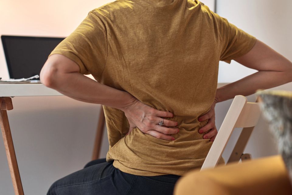 A woman working on a laptop at home and having problems with hips and lower back