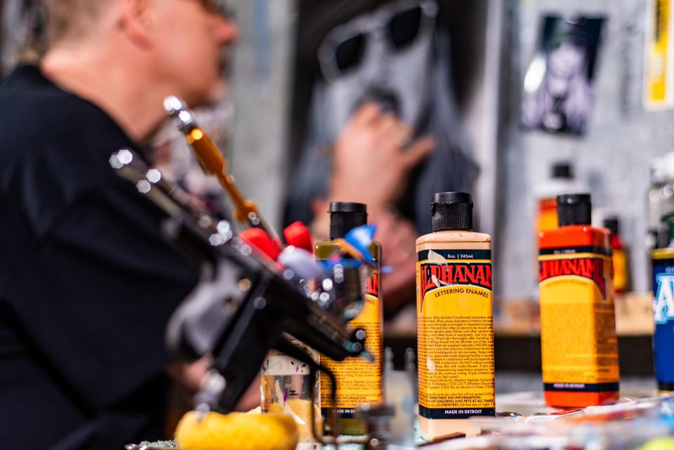 Paint bottles and airbrush tools while Skeeter creates custom artwork in the background.