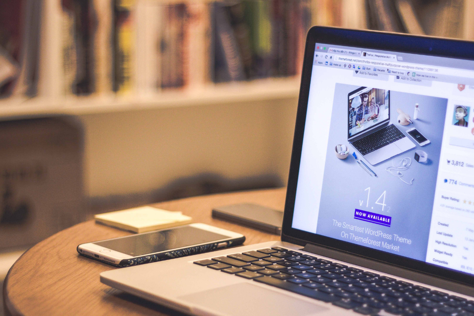 Computer sitting on a desktop with a screen showing a website theme