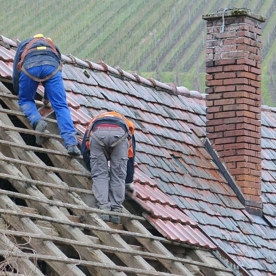 Two person putting roof tiles on roof at daytime