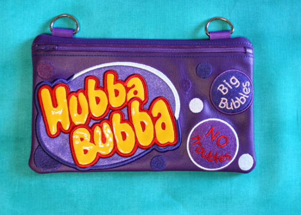 Custom embroidered purple zipper pouch inspired by Hubba Bubba bubble gum packaging with colorful lettering and bubble graphics.