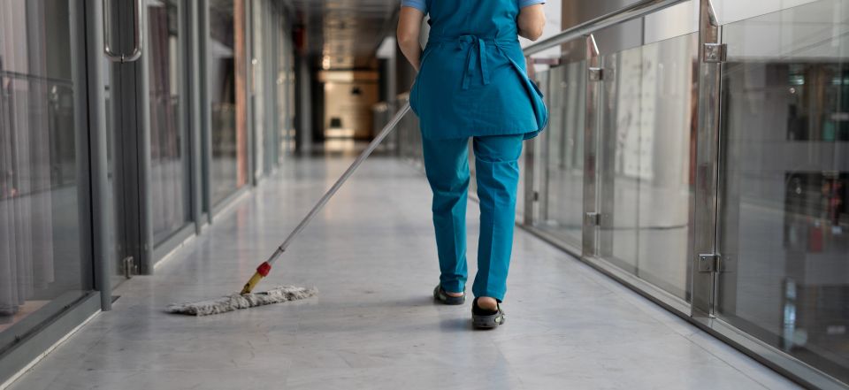 A professional cleaner in uniform mopping an office floor, representing commercial cleaning website design by Cannone Marketing.