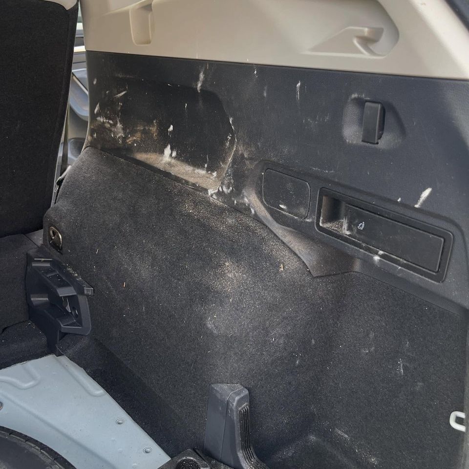 Dusty SUV cargo side panel covered in debris and residue before interior cleaning