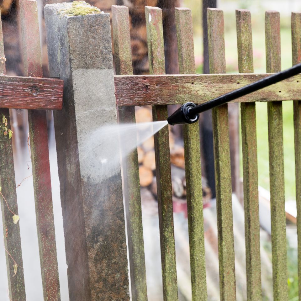 Cleaning dirty garden fence post with high pressure washer