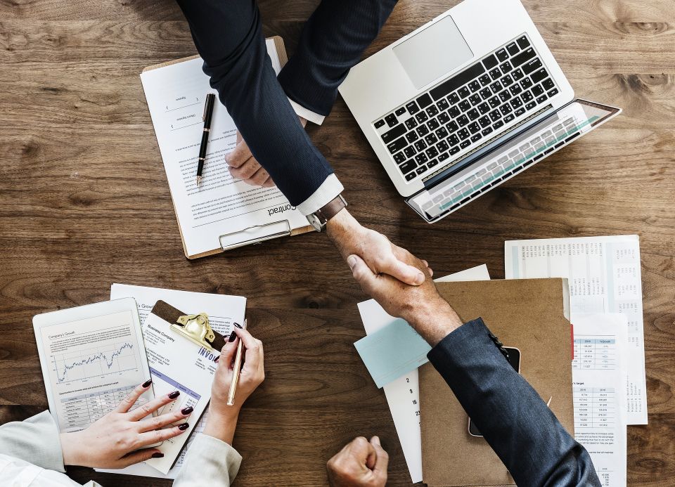 Two people shaking hands over a signed contract