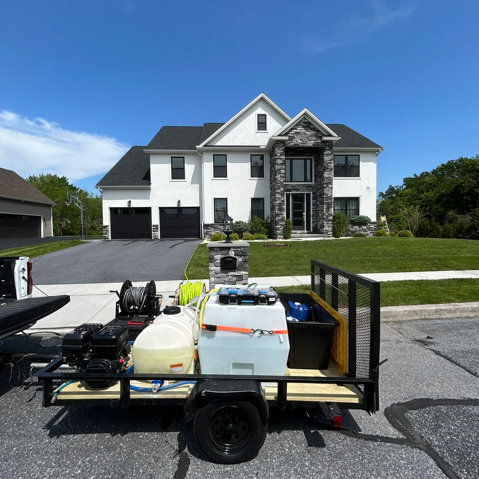 Pressure washing trailer with tanks and hoses parked outside large stucco home in Harrisburg PA 