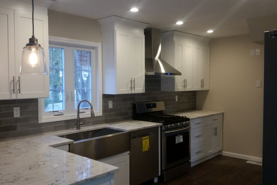 Modern kitchen renovation with marble countertops and pendant lighting.