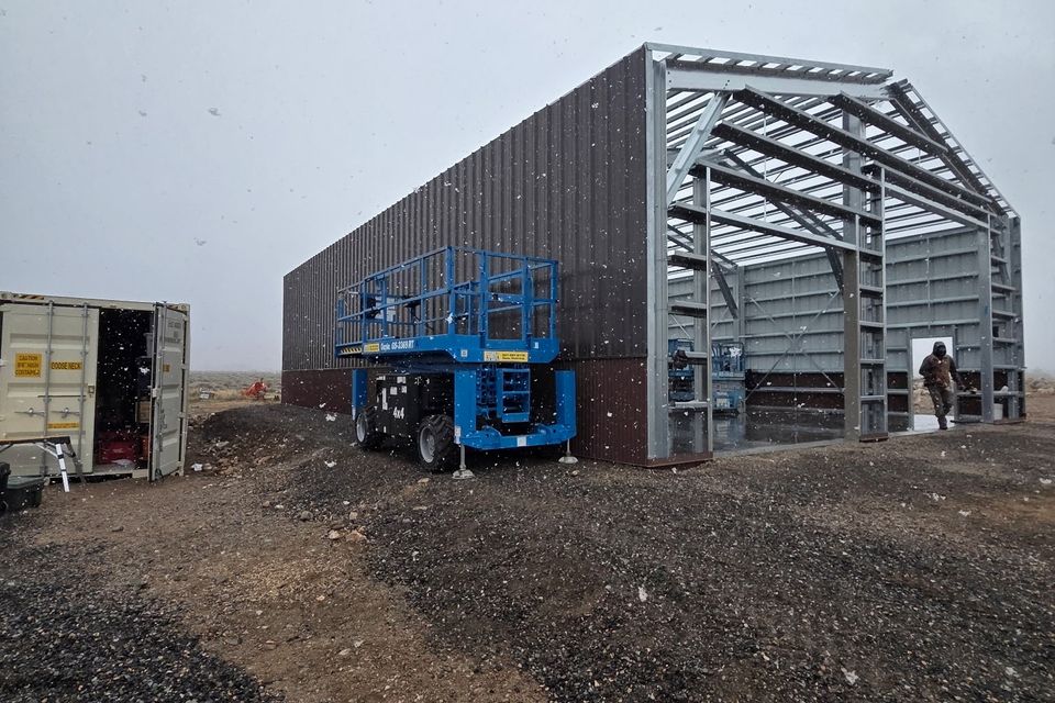 Metal building framing and wall panels going up with scissor lift on site in Trout Creek Montana