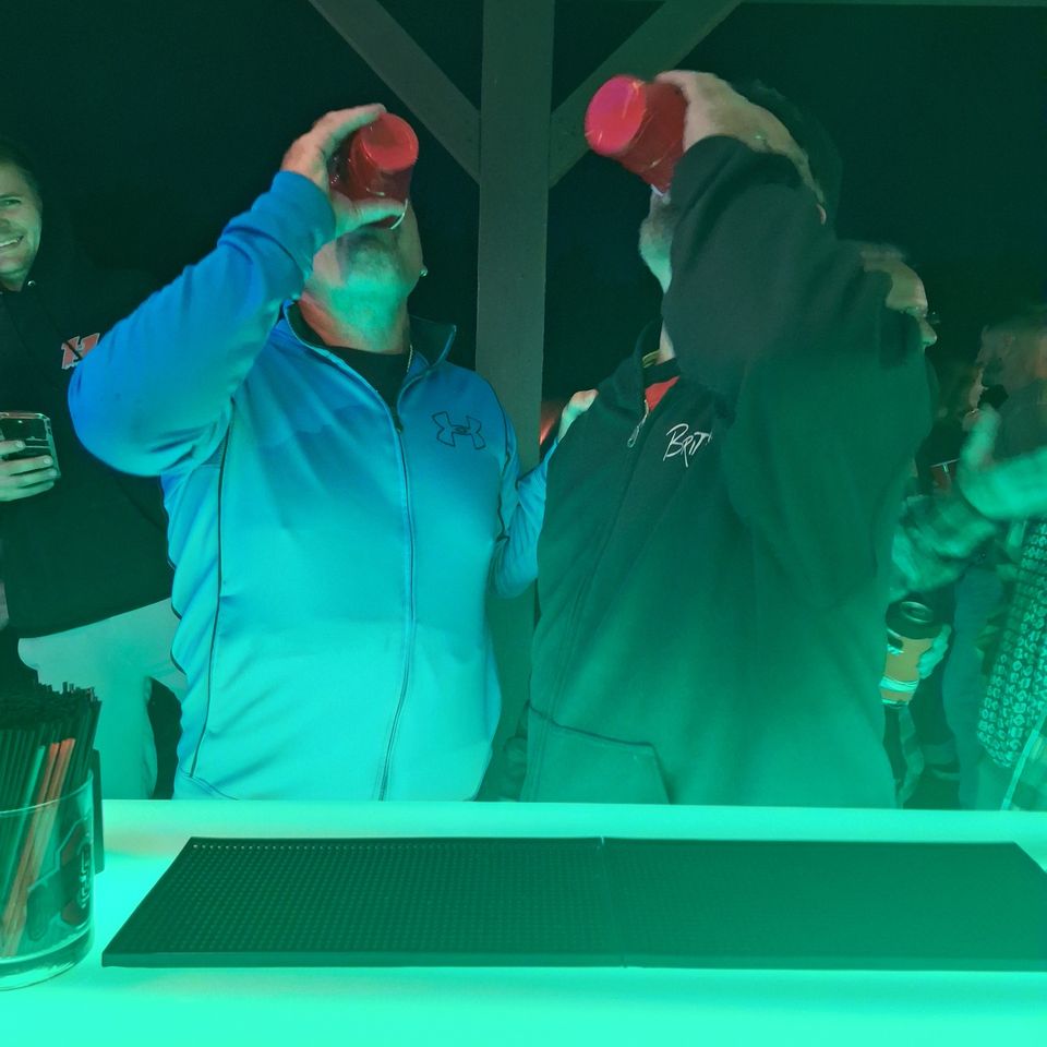 Two men taking shots at the full bar during a private party