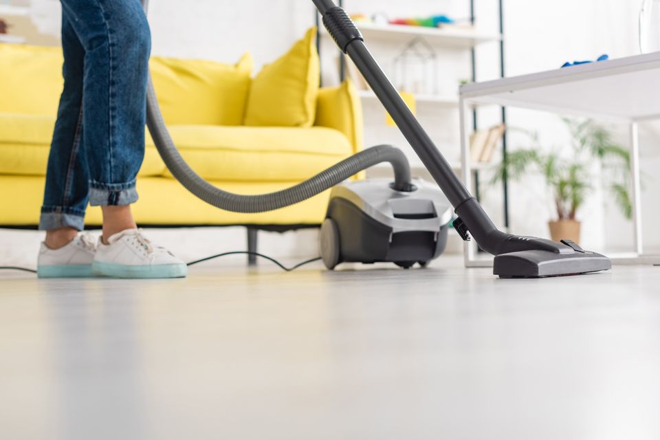A cropped view of a person vacuuming her floor