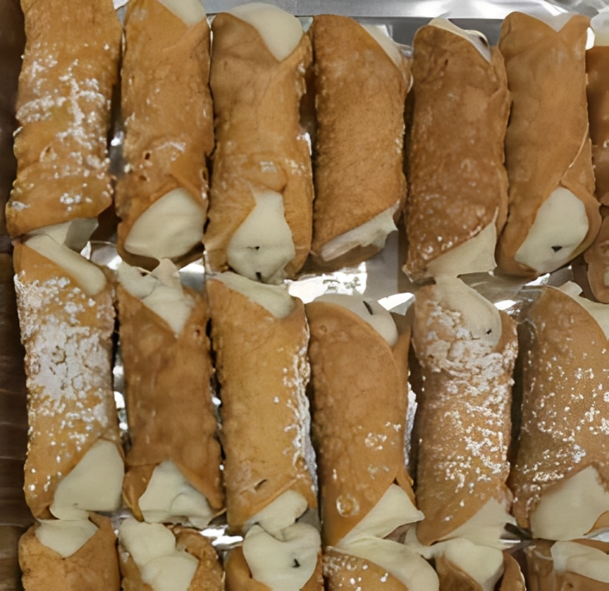 Tray of mini cannoli filled with sweet cream and dusted with powdered sugar.