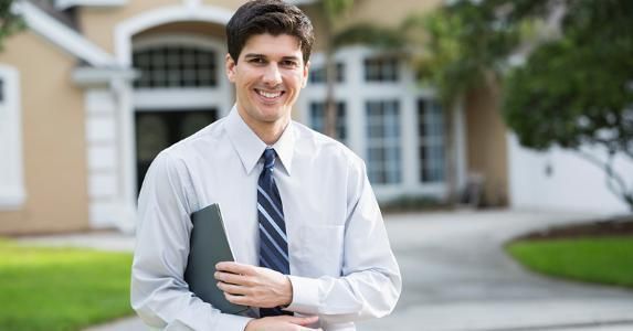 Bizsitesetreal estate agent smiling standing outside large house 573x30020170122 28713 1h092oy