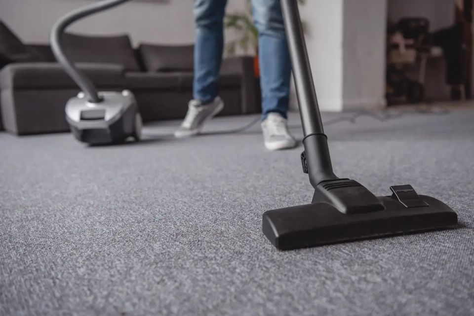 Vacuuming gray carpet in living room during house cleaning service in Virginia Beach VA