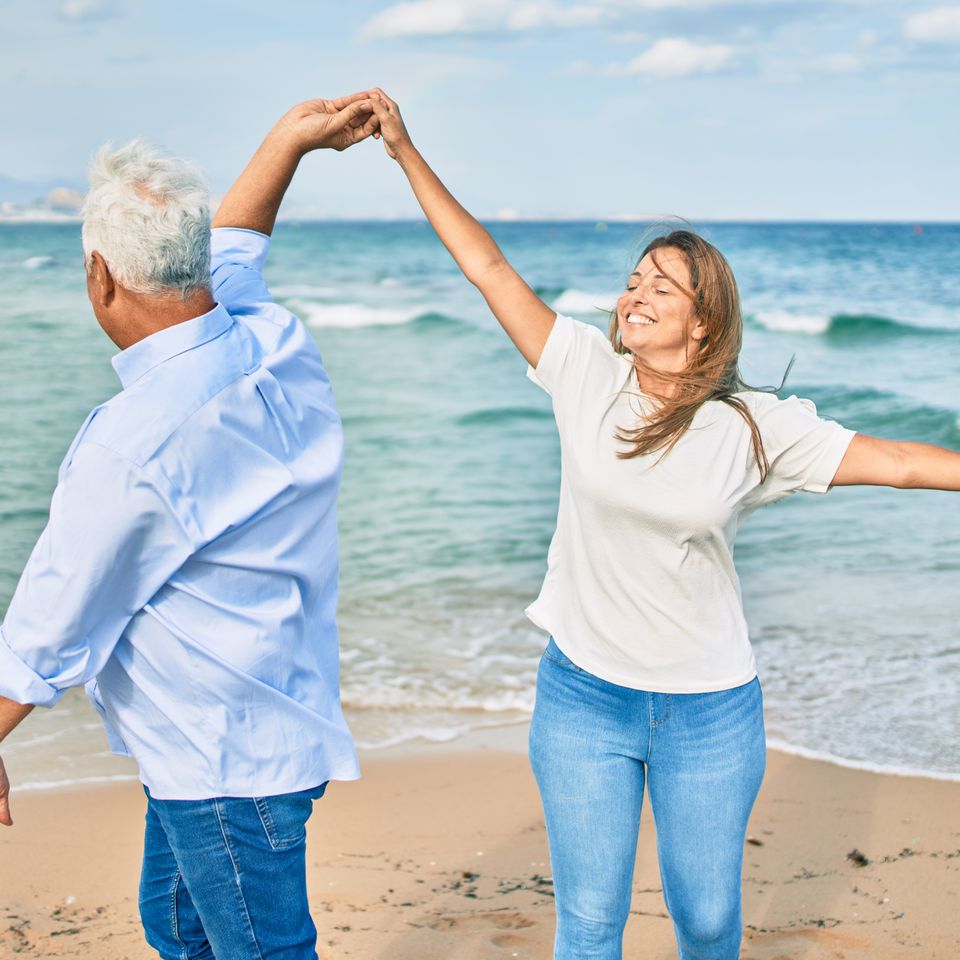 Middle age couple in love dancing at the beach happy and cheerful together