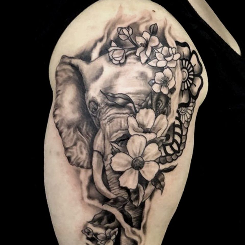 Elephnat tattoo with flowers on arm