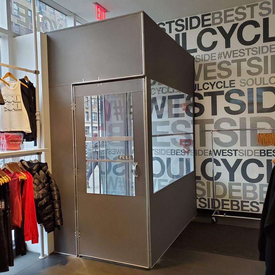 Brushed aluminum vestibule with a glazed door built inside a retail store entrance, photographed from the sales floor