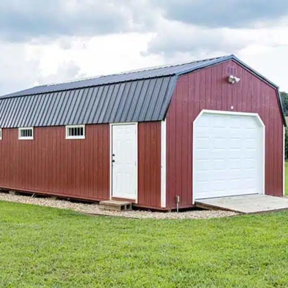 Red high wall garage with white overhead door and loft windows on an East Tennessee property