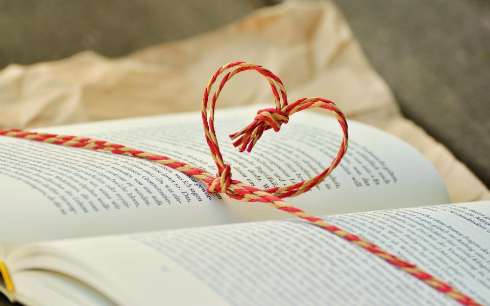 “Heart-shaped string on an open book symbolizing compassion, reflection, and mission-centered values.”