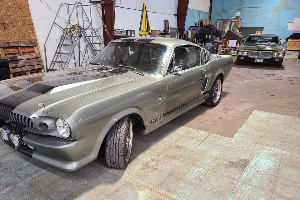 Classic silver car inside a repair shop awaiting professional auto glass service.