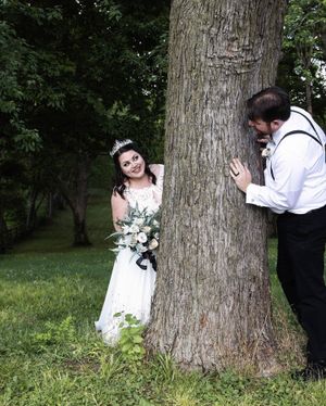 Bride and groom playing hide and seek behind a tree