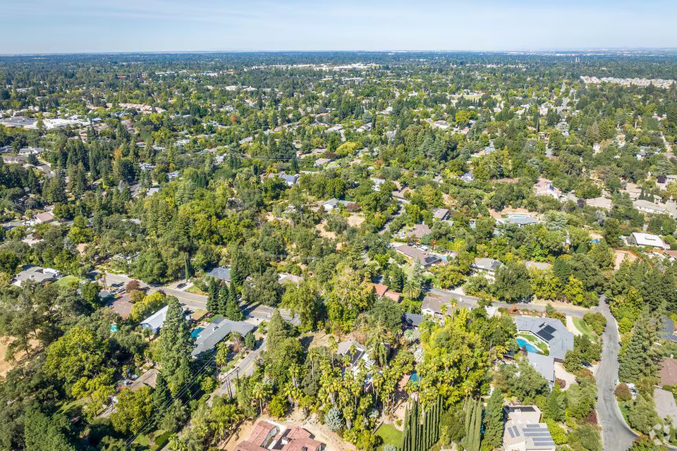 Aerial view of the Fair Oaks, California landscape, showcasing the dense tree canopy, the American River, and the historic Fair Oaks Village neighborhood.