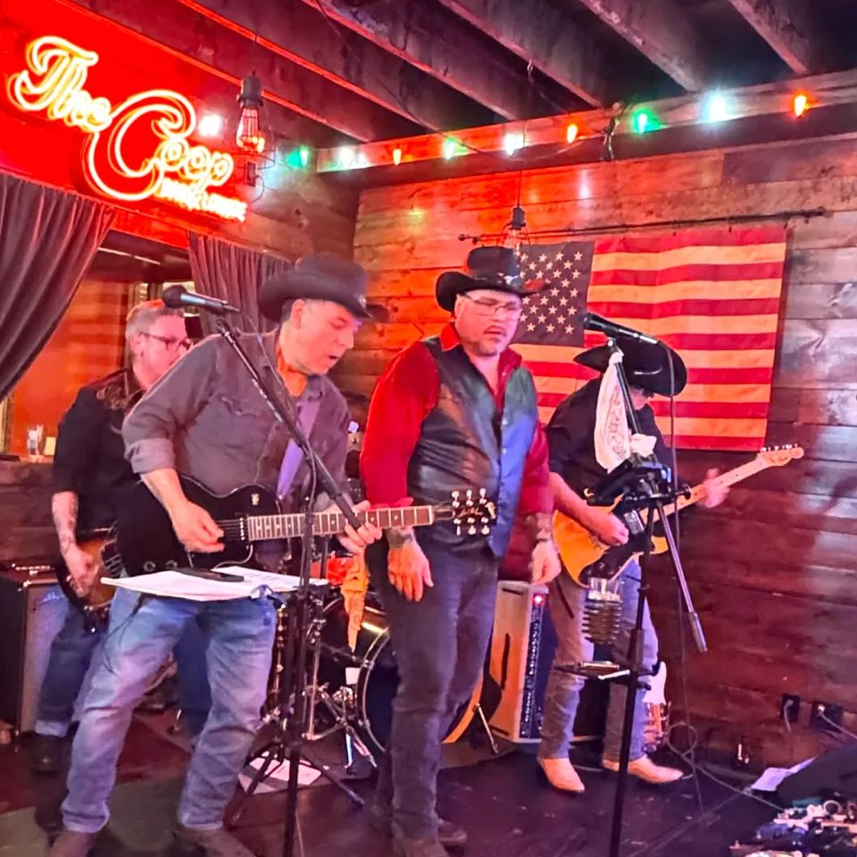 Roadside band members in cowboy hats performing guitars and vocals on stage at a Long Island NY bar