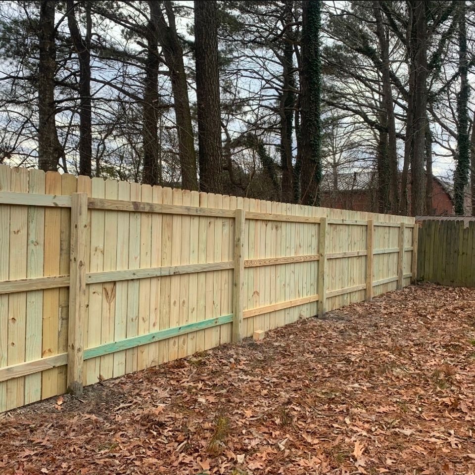 Wood dog-ear privacy fence with horizontal rails installed along wooded backyard in Virginia Beach VA